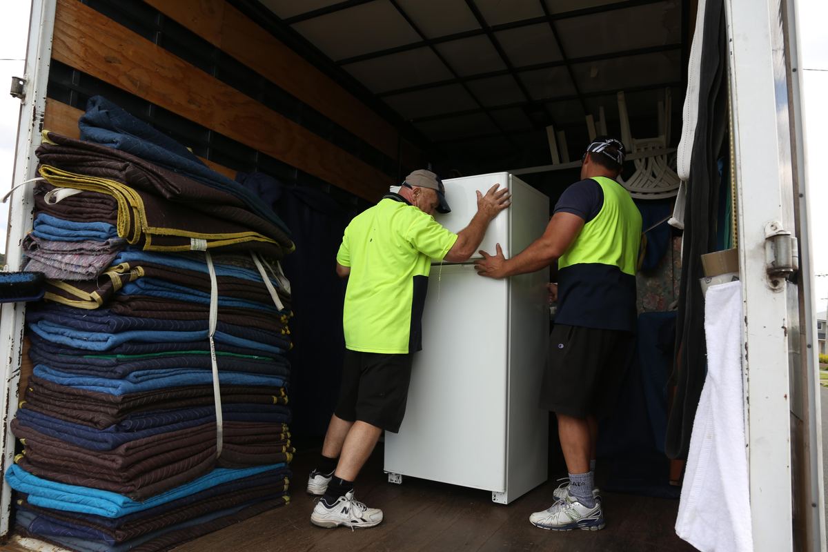 Two-person junk removal crew loading furniture into a truck
